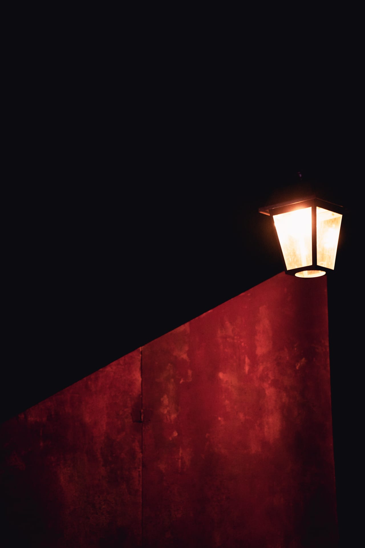 Un réverbère à gaz au plateau, baigné d'une lumière rouge, décor seul des Oubliées de Londres